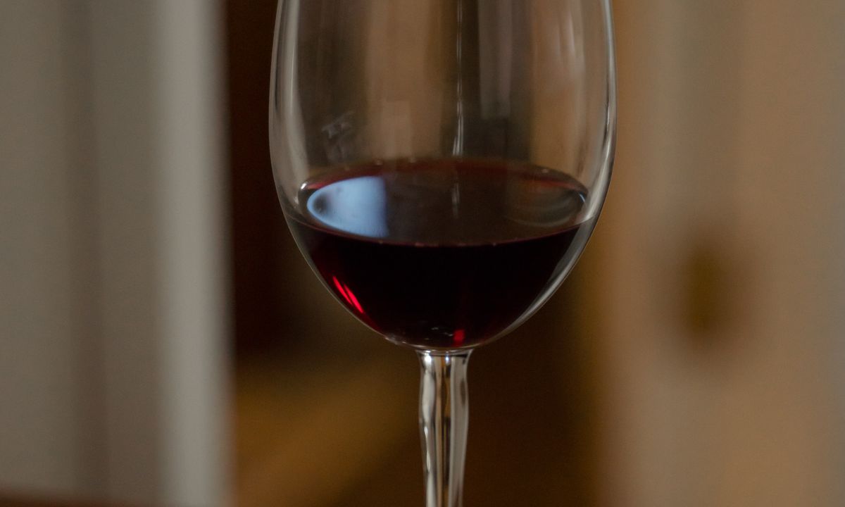 A single glass of red wine resting on a wooden table