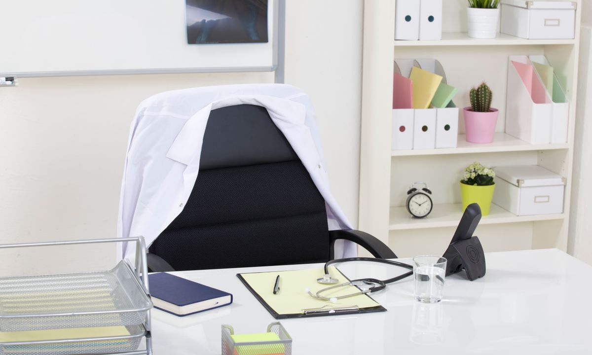 An unoccupied consultation desk with a stethoscope and paper