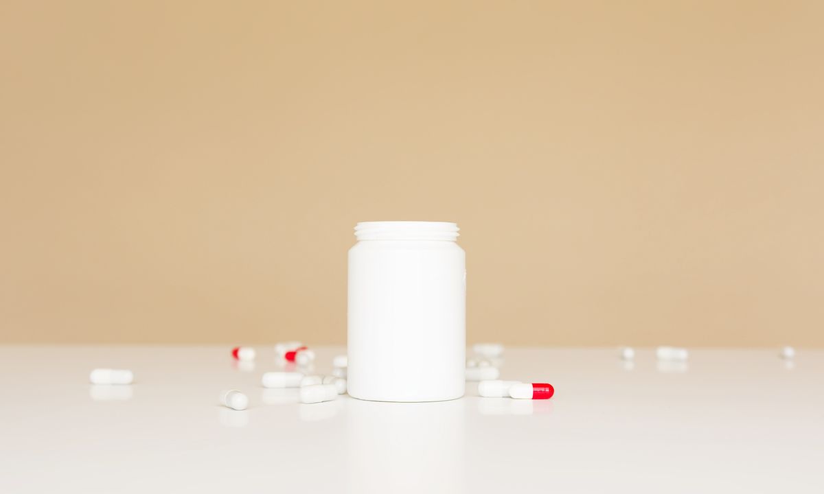 Open prescription-style bottle with red-and-white capsules arranged on a table