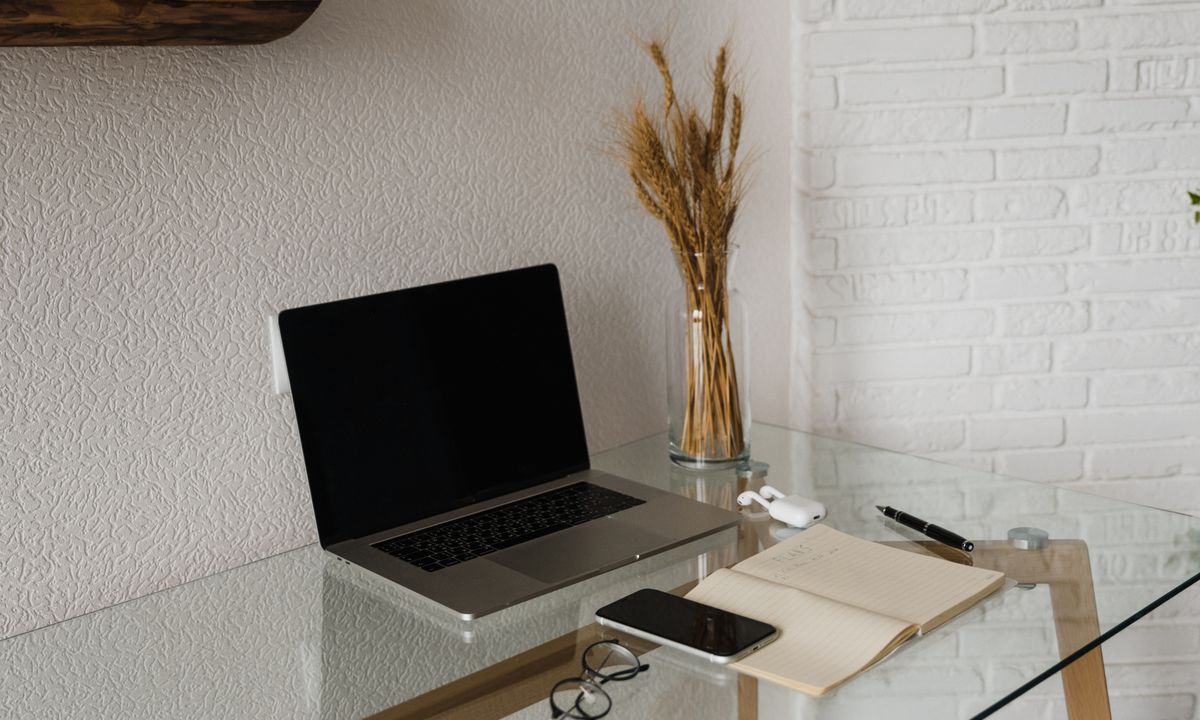 Laptop, smartphone and notepad on a glass desk