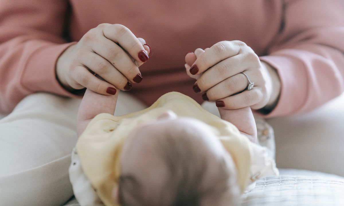 Close-up of a parent's hands gently holding a baby's hands